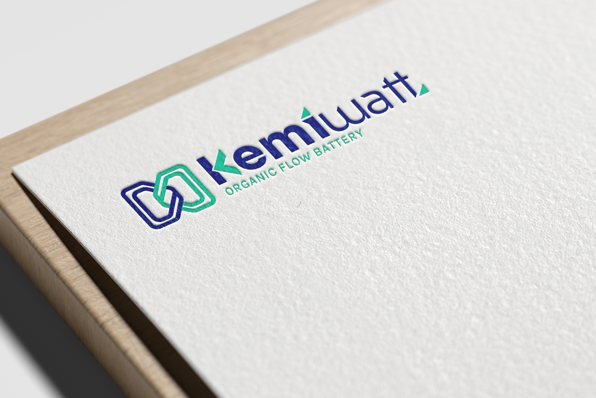 Gros plan sur un papier blanc texturé, sur lequel sont imprimés le logo bleu et vert de Kemiwatt ainsi que la mention « Kemiwatt Organic Flow Battery », posé sur une surface en bois.